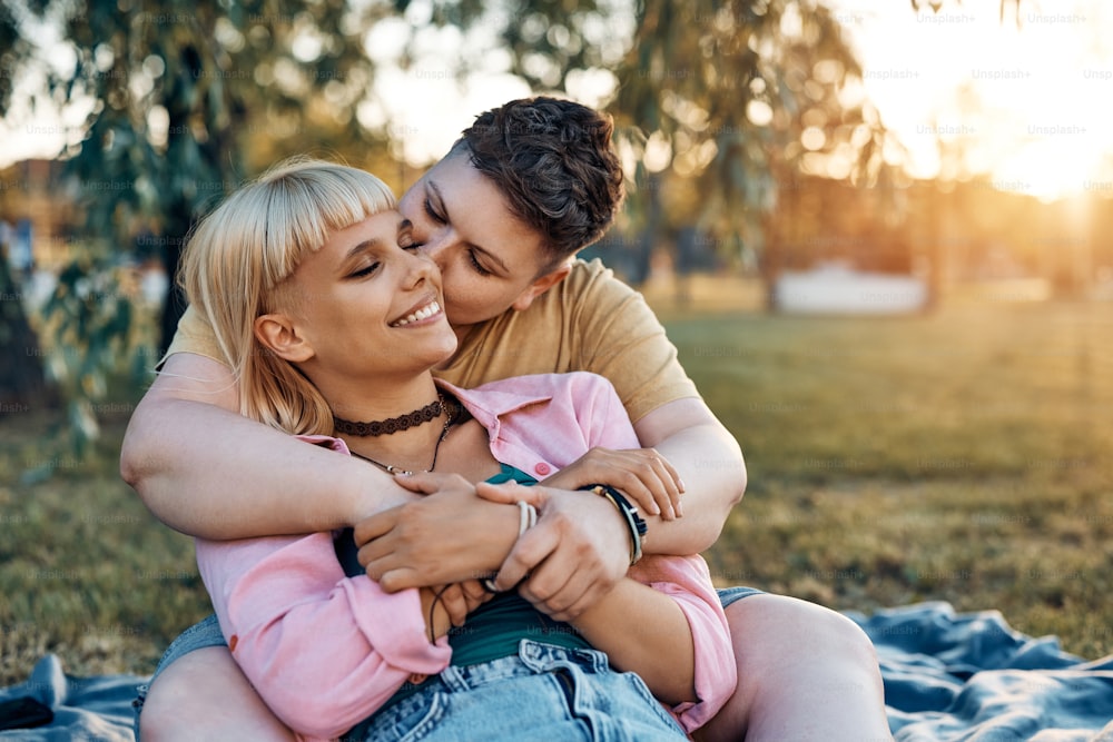 Young female couple enjoying in their love while relaxing in the park at sunset.