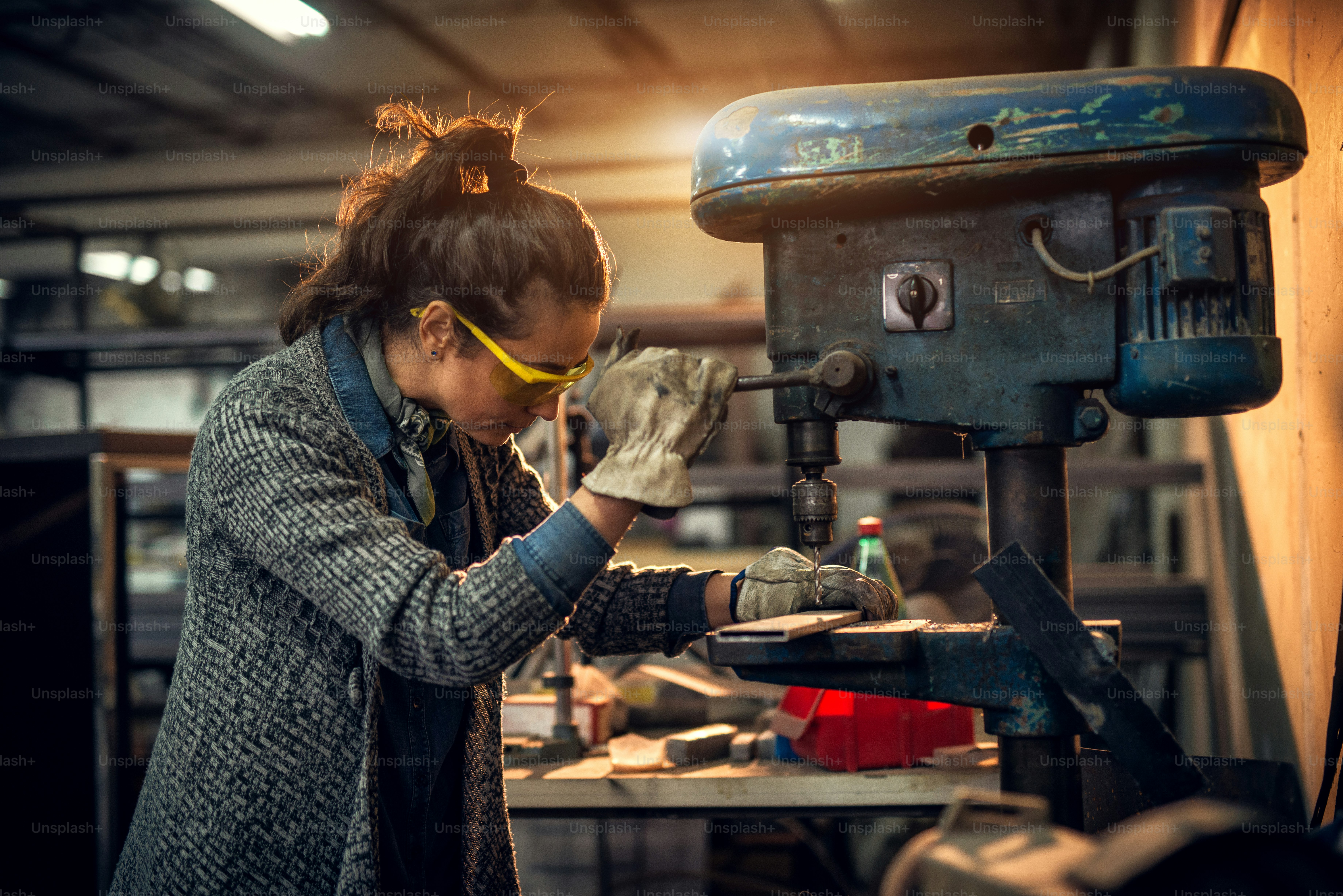 Portrait view of focused serious middle aged professional female carpentry working with an electric drill in the workshop.