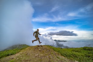 El hombre que corre en la montaña sobre un fondo de cielo nublado