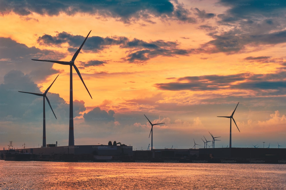 Turbinas eólicas alimentam geradores de eletricidade no porto de Antuérpia ao pôr do sol. Antuérpia, Bélgica