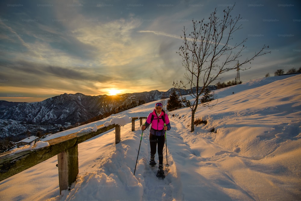 美しい夕暮れの日にスノーシューハイキングで一人で若い女性