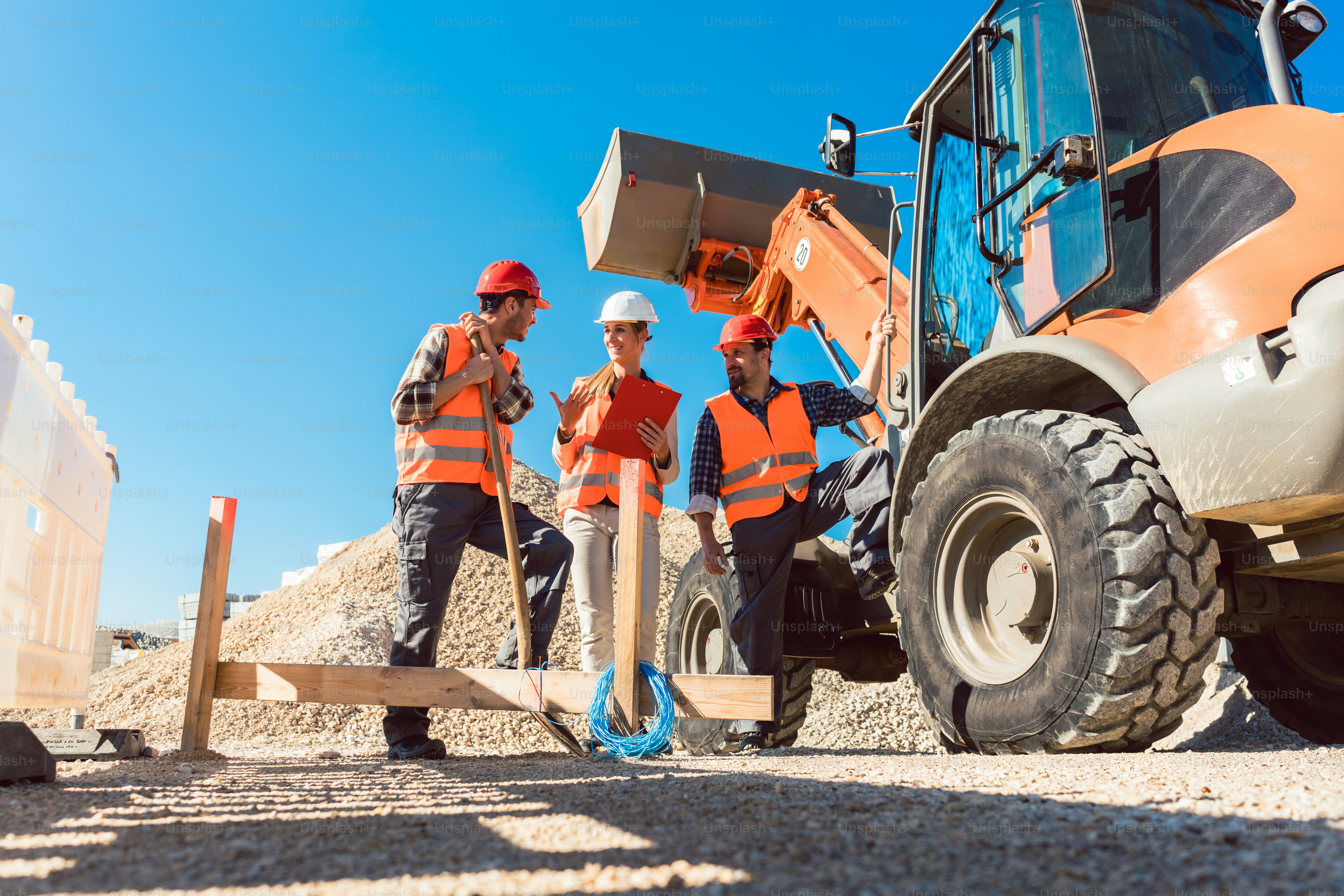 Three workers on roadwork construction site discussing