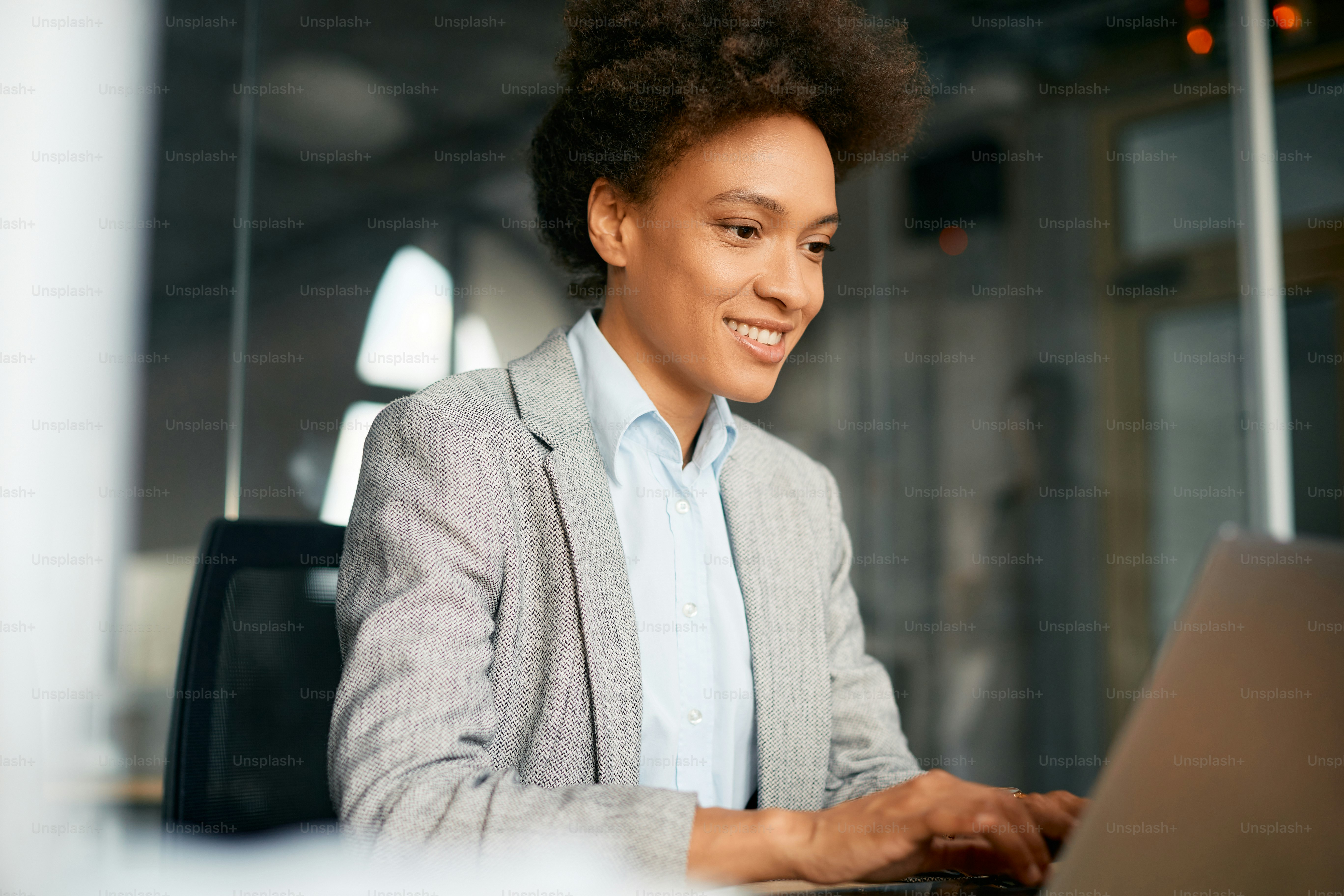 Happy African American businesswoman using laptop while working in the office