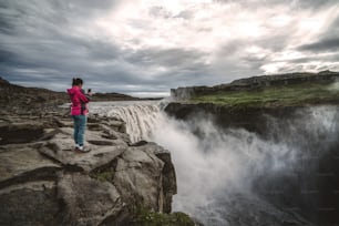 Femme voyageuse dans le magnifique paysage islandais de la cascade de Dettifoss dans le nord-est de l’Islande. Dettifoss est une cascade du parc national de Vatnajokull réputée pour être la cascade la plus puissante d’Europe.