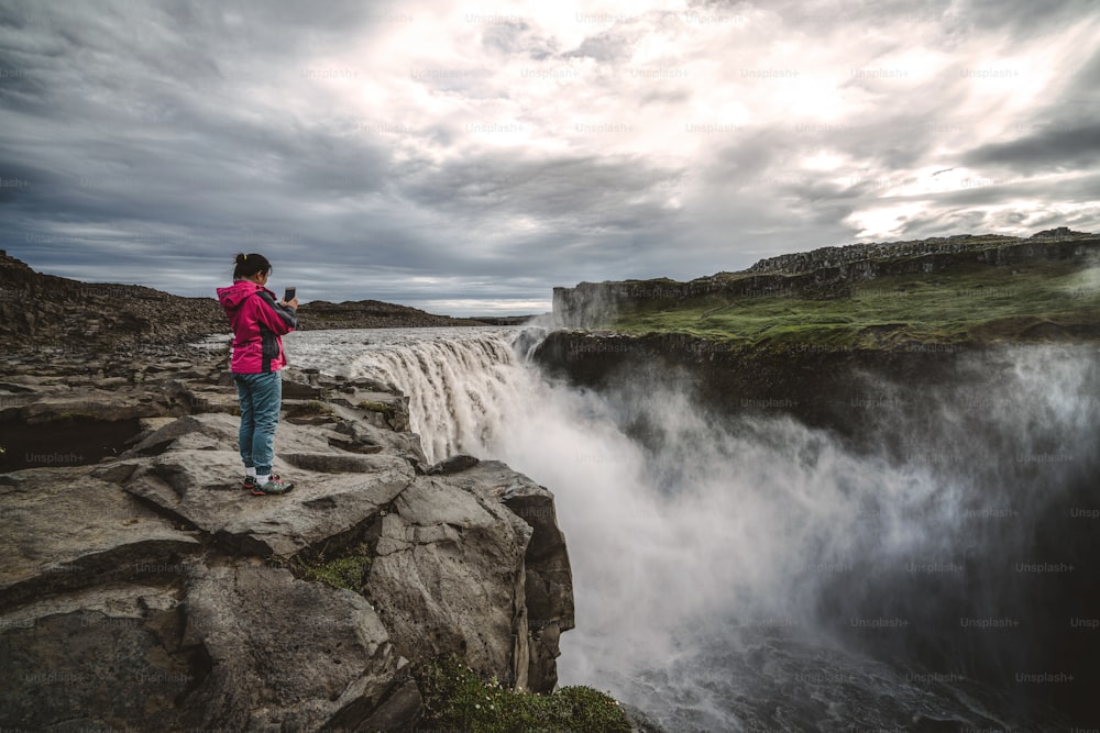 Mujer viajera en el increíble paisaje islandés de la cascada de Dettifoss en el noreste de Islandia. Dettifoss es una cascada en el Parque Nacional de Vatnajökull que tiene fama de ser la cascada más poderosa de Europa.