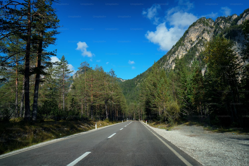 Beautiful mountain road with trees, forest and mountains in the backgrounds. Taken at state highway road of Dolomites mountain in Italy.