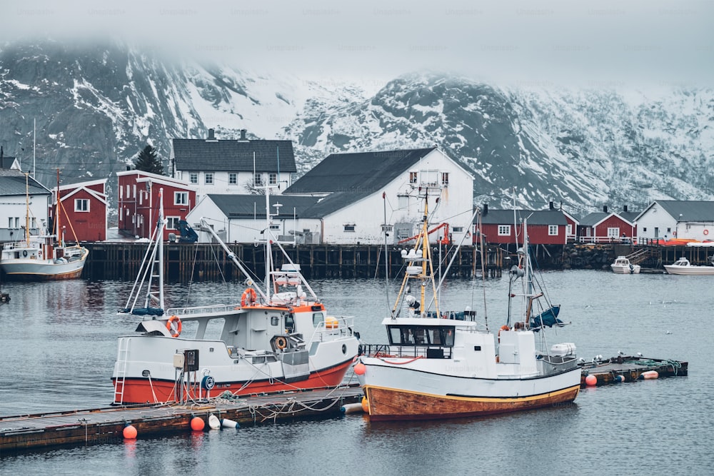 Pier with ships in Hamnoy fishing village on Lofoten Islands, Norway with red rorbu houses in winter