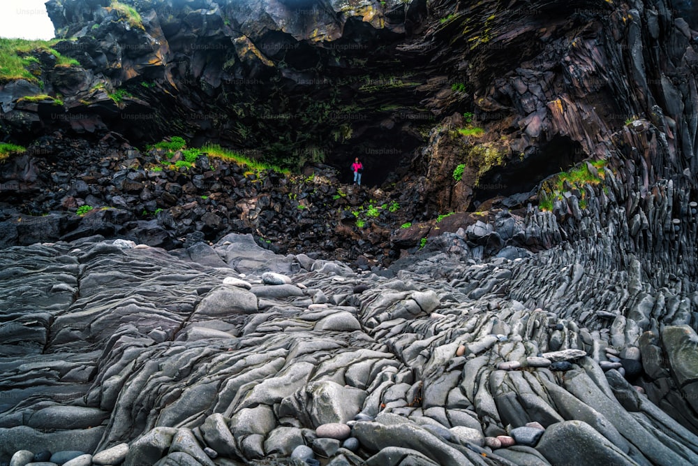 Traveler hiking in rocky coastline landscape in Hellnar, Iceland. Hellnar was among the largest fishing villages beneath the Snaefellsjokull ice cap in West Iceland.