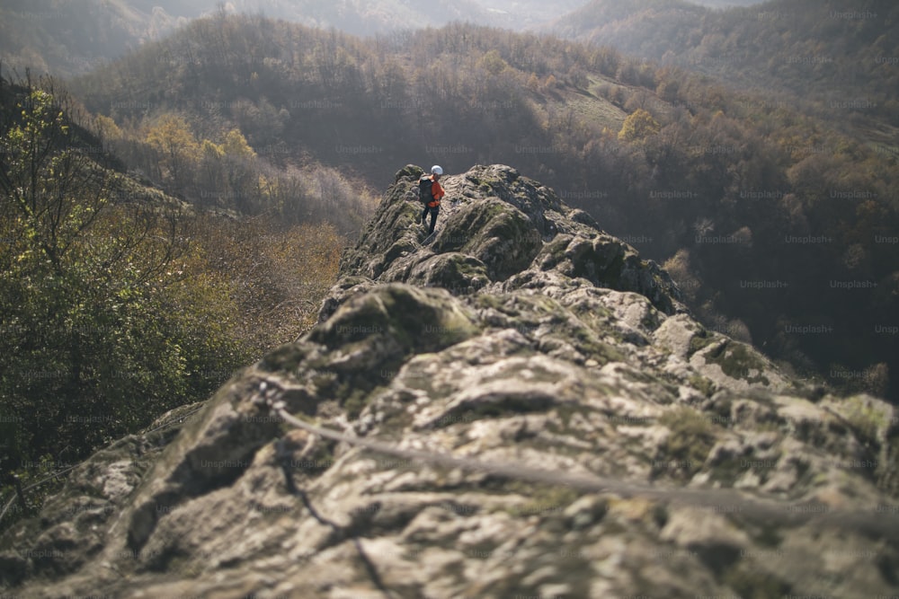 Homem totalmente equipado escalando montanha ao longo de uma via ferrata.