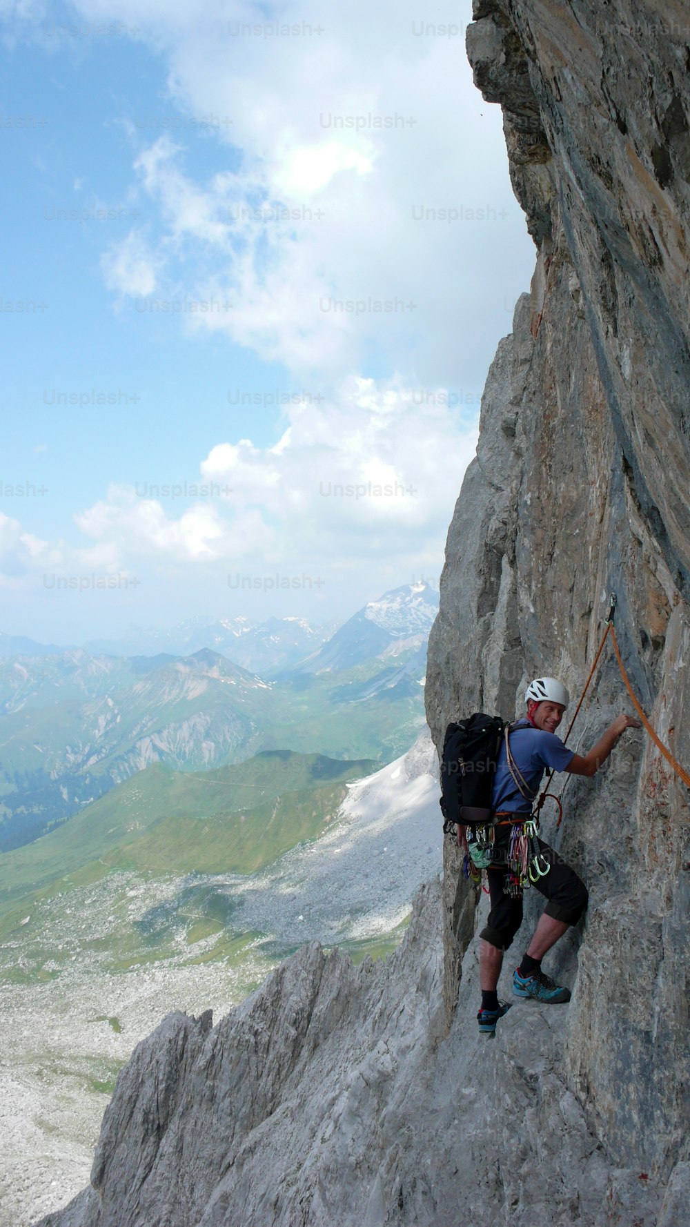 Un atractivo alpinista de mediana edad en una empinada ruta de escalada en roca en los Alpes suizos, cerca de Klosters