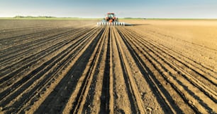Farmer with tractor seeding  crops at agricultural field