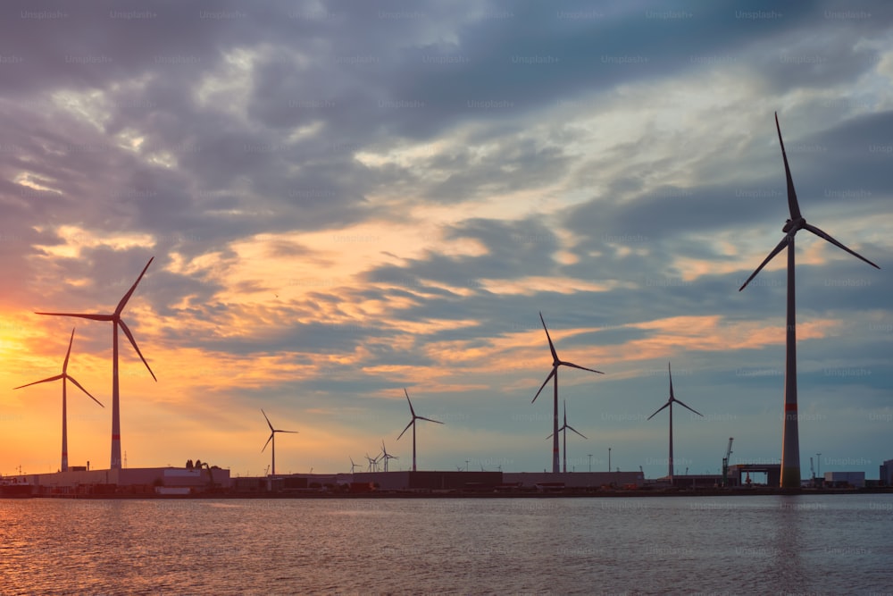 風力タービンは、日没時にアントワープ港の発電機に電力を供給します。ベルギー、アントワープ