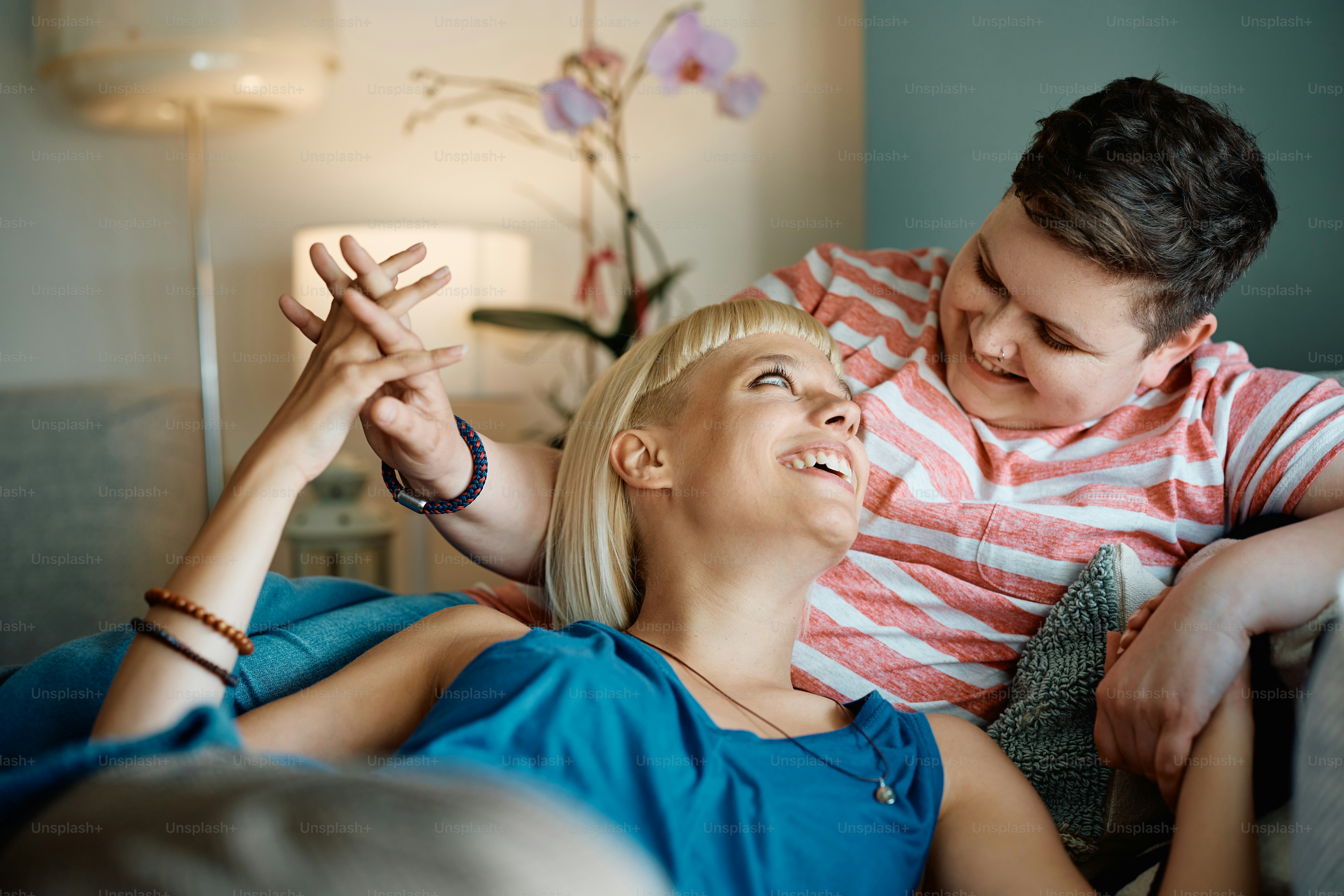 Happy lesbian couple holding hand and talking while relaxing at home.