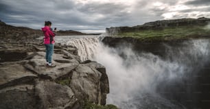 Femme voyageuse dans le magnifique paysage islandais de la cascade de Dettifoss dans le nord-est de l’Islande. Dettifoss est une cascade du parc national de Vatnajokull réputée pour être la cascade la plus puissante d’Europe.