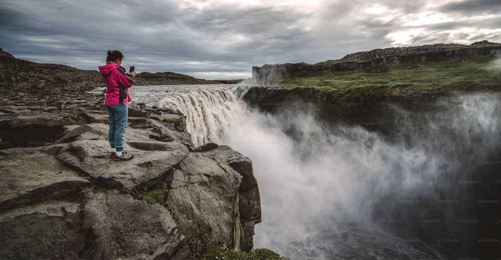 Femme voyageuse dans le magnifique paysage islandais de la cascade de Dettifoss dans le nord-est de l’Islande. Dettifoss est une cascade du parc national de Vatnajokull réputée pour �être la cascade la plus puissante d’Europe.