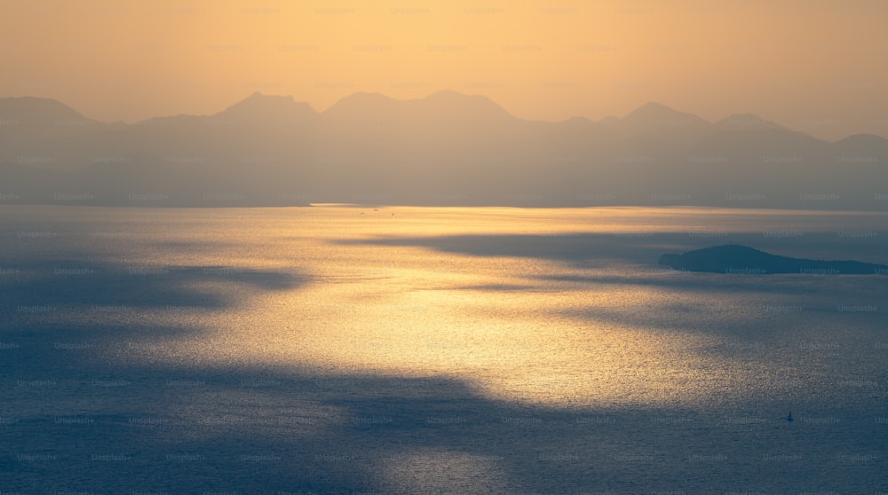 Majestuoso juego de luces y sombras formado por el sol poniente sobre la superficie ondulada del mar Mediterráneo. Paisaje marino cambiante y atmosférico