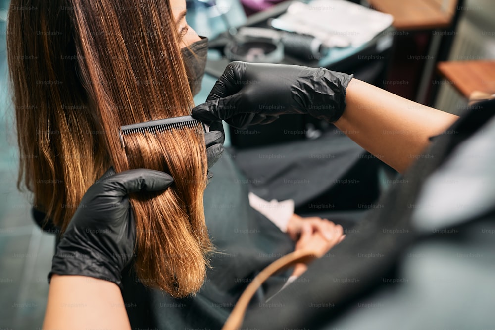 Close-up do cabeleireiro penteando o cabelo da mulher durante a consulta no salão de cabeleireiro.