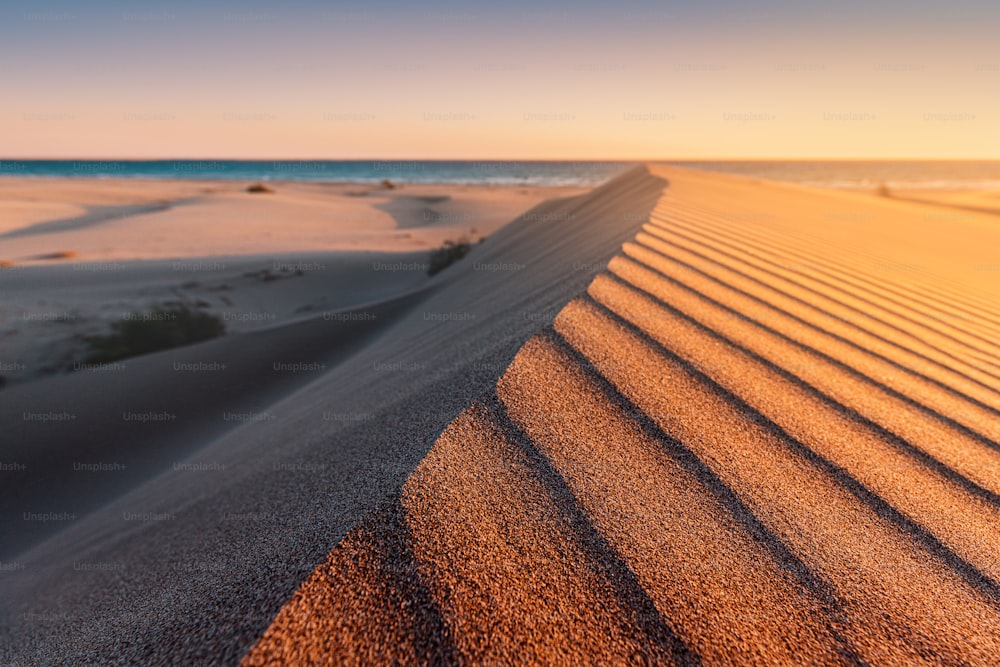 La plage de Patara est un célèbre site touristique et une destination naturelle en Turquie. Vue majestueuse sur les dunes de sable orange et les collines brille dans les rayons du coucher de soleil chaud.