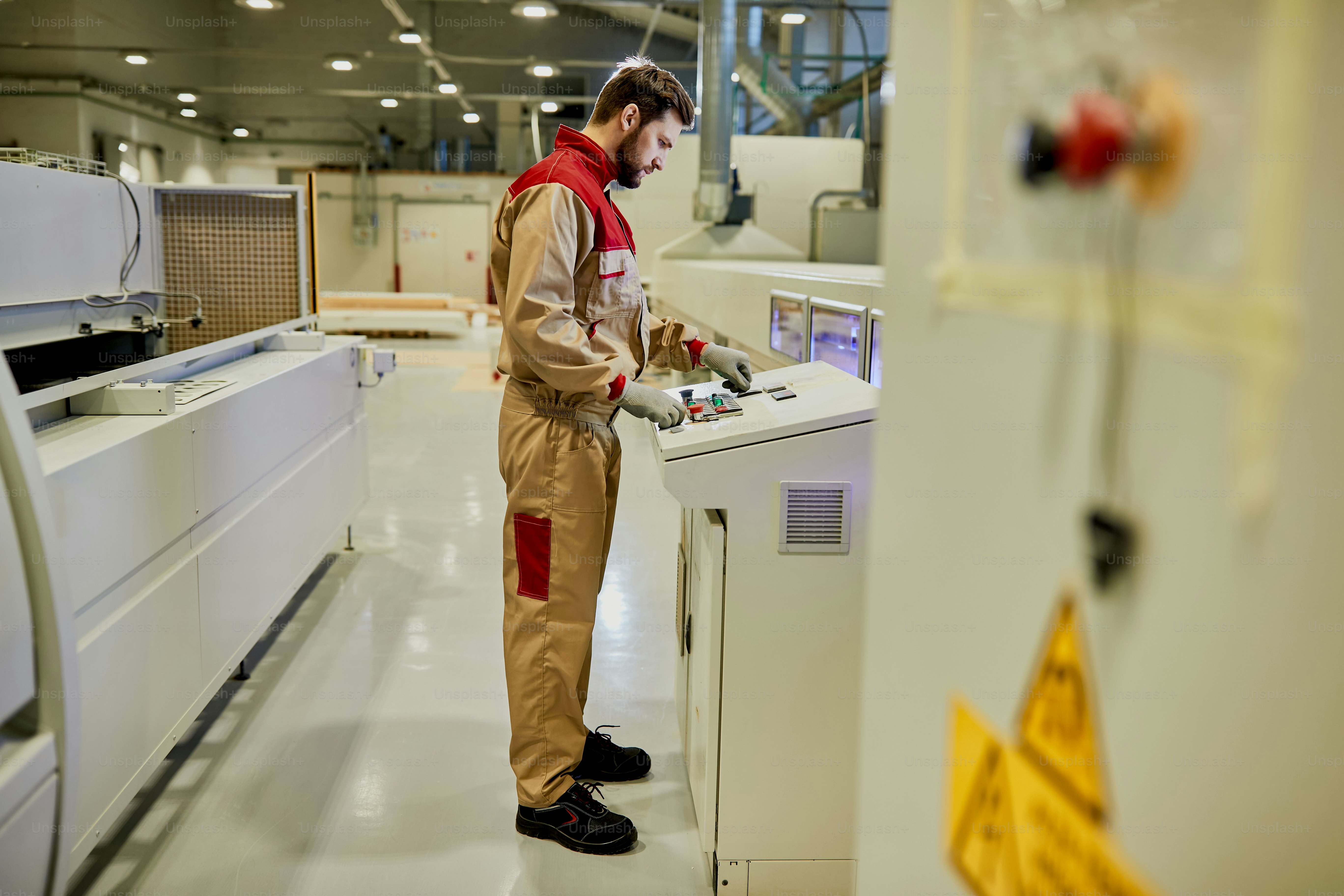Male worker using touchpad while supervising automated production line ...