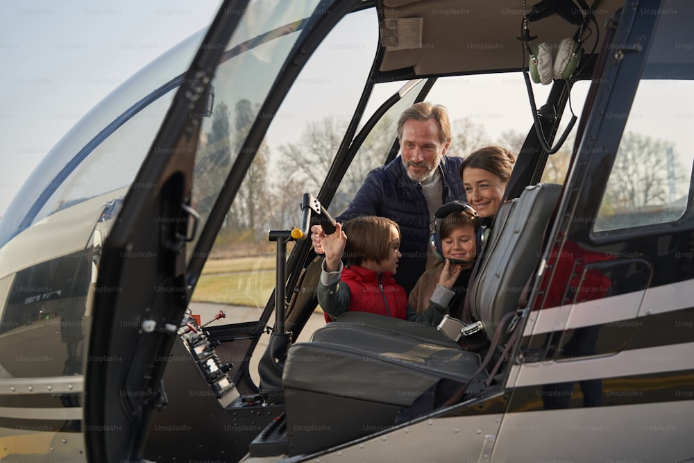 Maman et papa attentionnés laissant leurs enfants explorer à l’intérieur de l’hélicoptère
