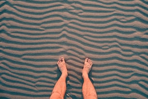 O viajante relaxa e descansa com os pés descalços na areia quente. O conceito das caminhadas e os problemas com a ortopedia, como os pés chatos