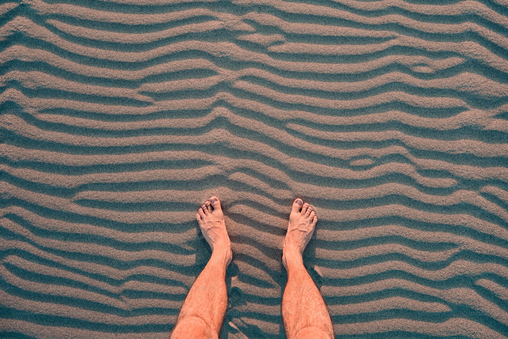 El viajero se relaja y descansa con los pies descalzos sobre la cálida arena. El concepto de las caminatas y los problemas con la ortopedia, como los pies planos