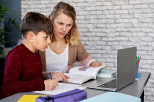 Boy doing homework while homeschooling mom teaches