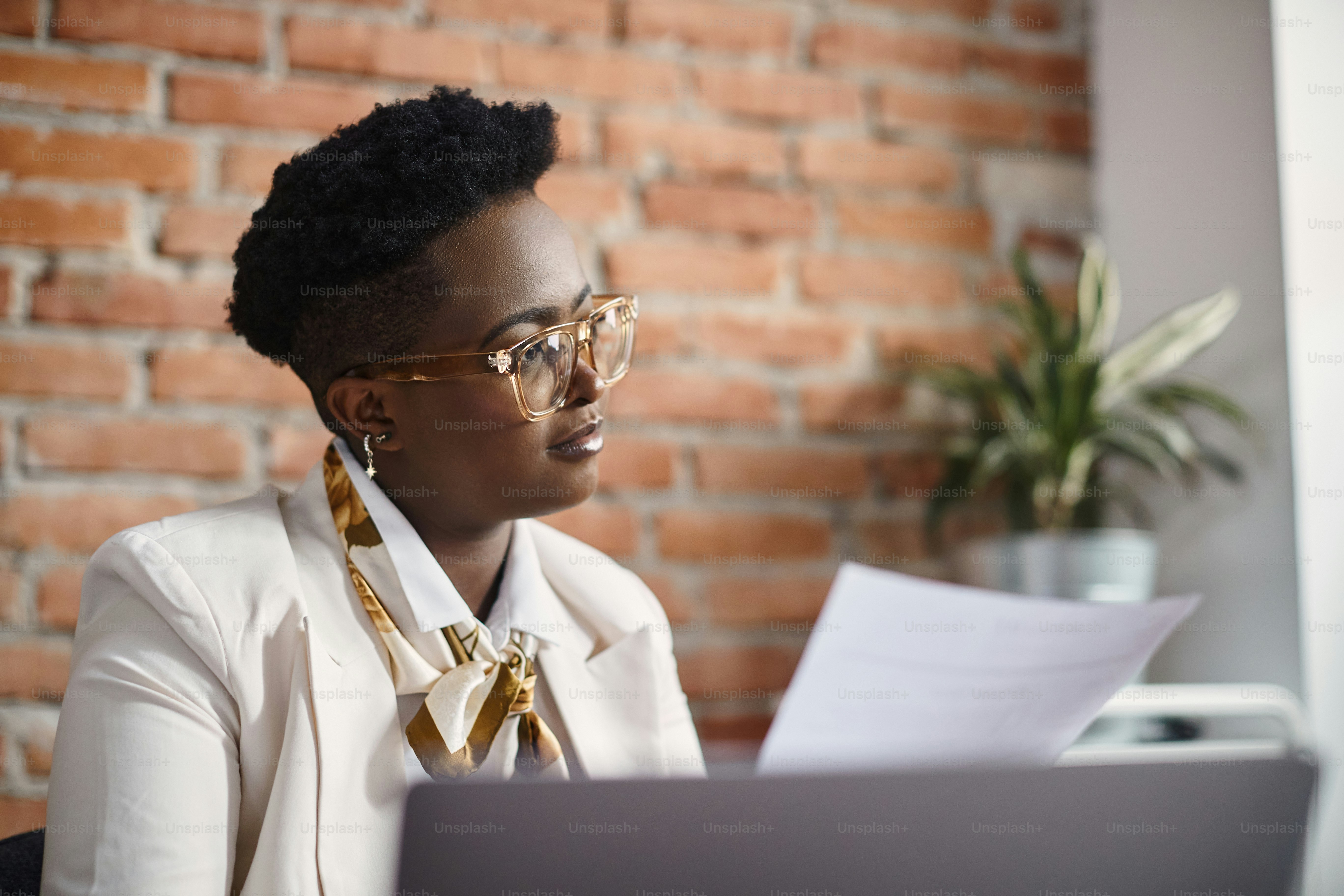 African American female entrepreneur analyzing business reports while working at corporate office
