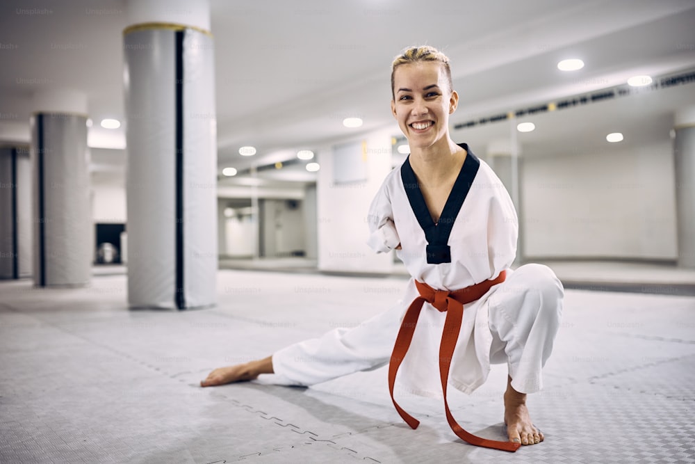 Combattente di taekwondo femminile motivata con para-abilità che si riscalda durante l'allenamento sportivo nel centro benessere e guardando la telecamera.