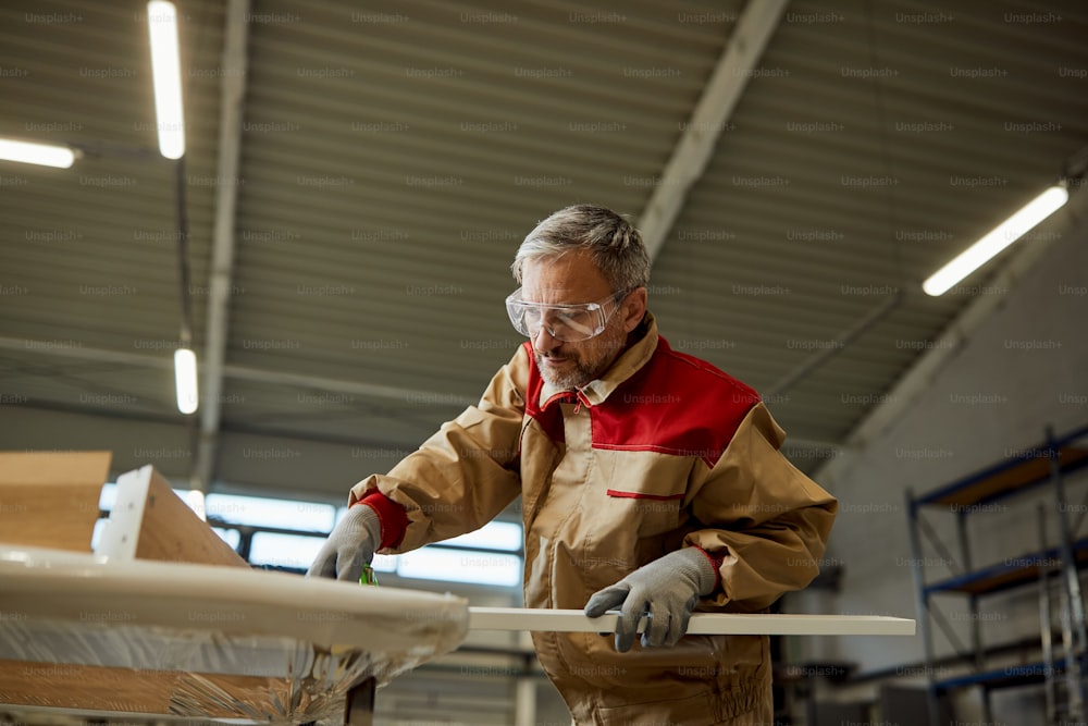 Vista sottostante dell'operaio maschio che effettua misurazioni mentre lavora con il legno presso l'officina di falegnameria.