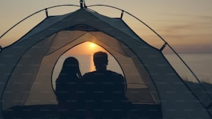 The man and woman sitting in the campsite tent near the sea