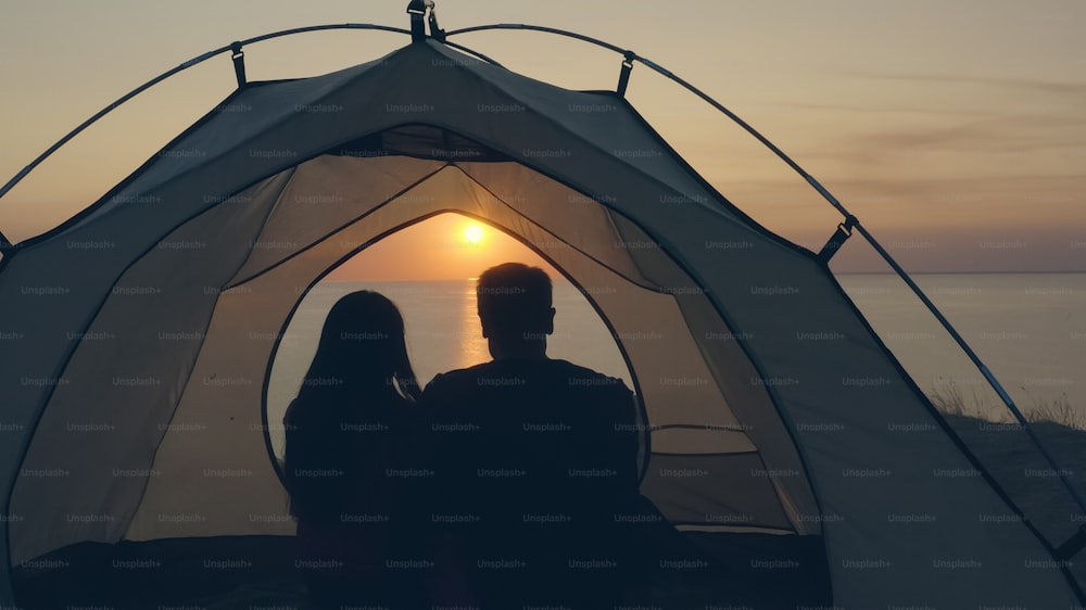 El hombre y la mujer sentados en la tienda del camping cerca del mar