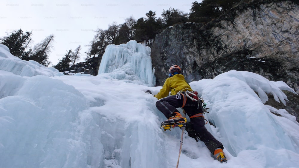 スイスアルプスの長くて急な氷瀑の最後のピッチに向かう男性登山家は、アイスクライミングのハードな一日の後、サンモリッツを熊に
