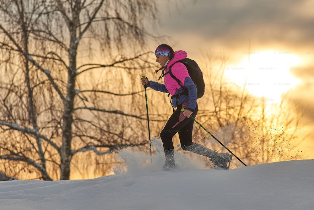 Una giovane ragazza sportiva corre con le racchette da neve