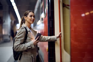 Passageira feliz do sexo feminino que entra no trem suburbano na estação.