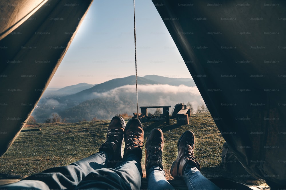 Close up of young couple enjoying the view of mountain range while lying in their tent