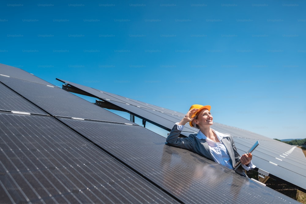Businesswoman or investor inspecting her solar farm standing in front of photovoltaic panels