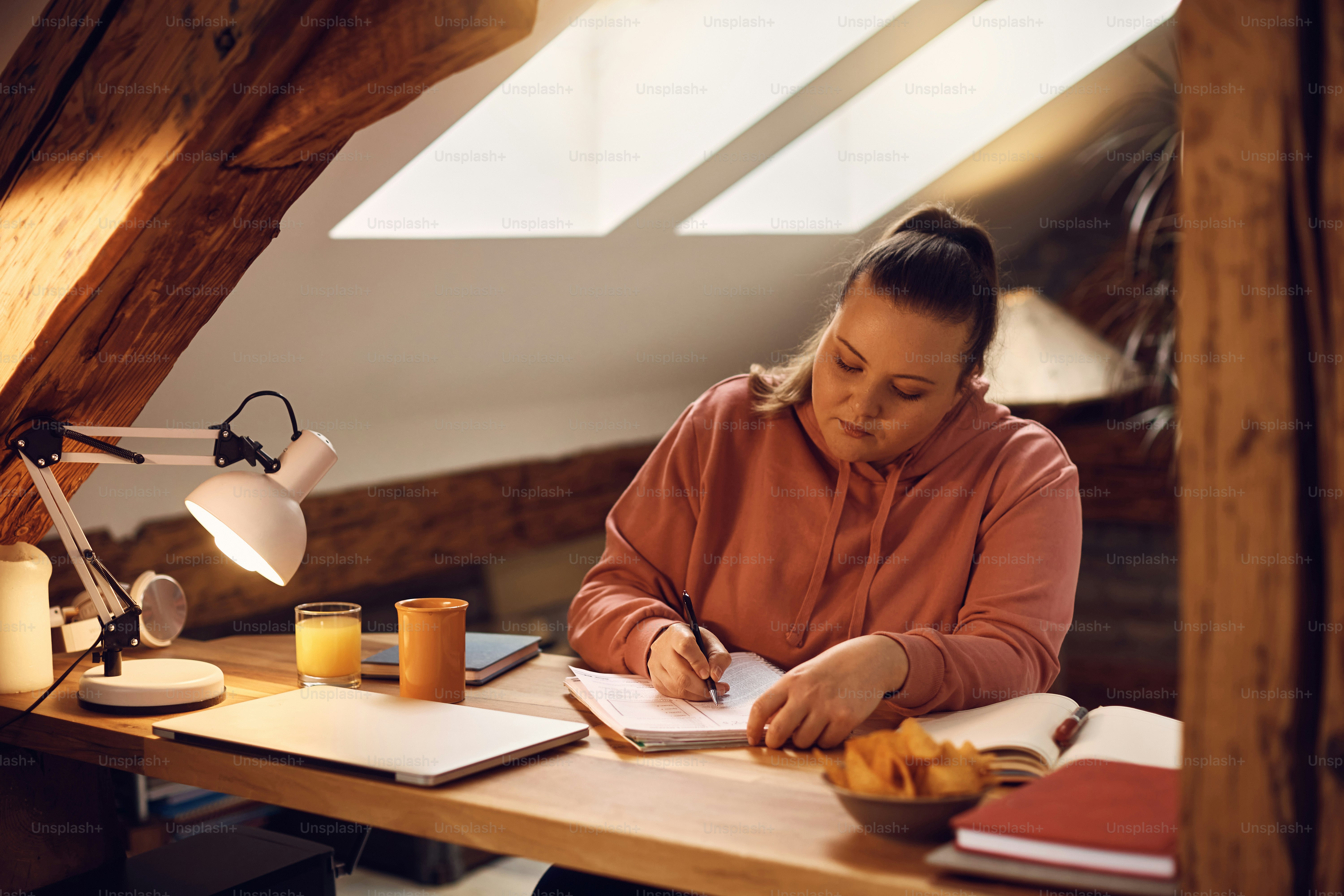 Young woman wearing headphones while studying for upcoming exams at ...