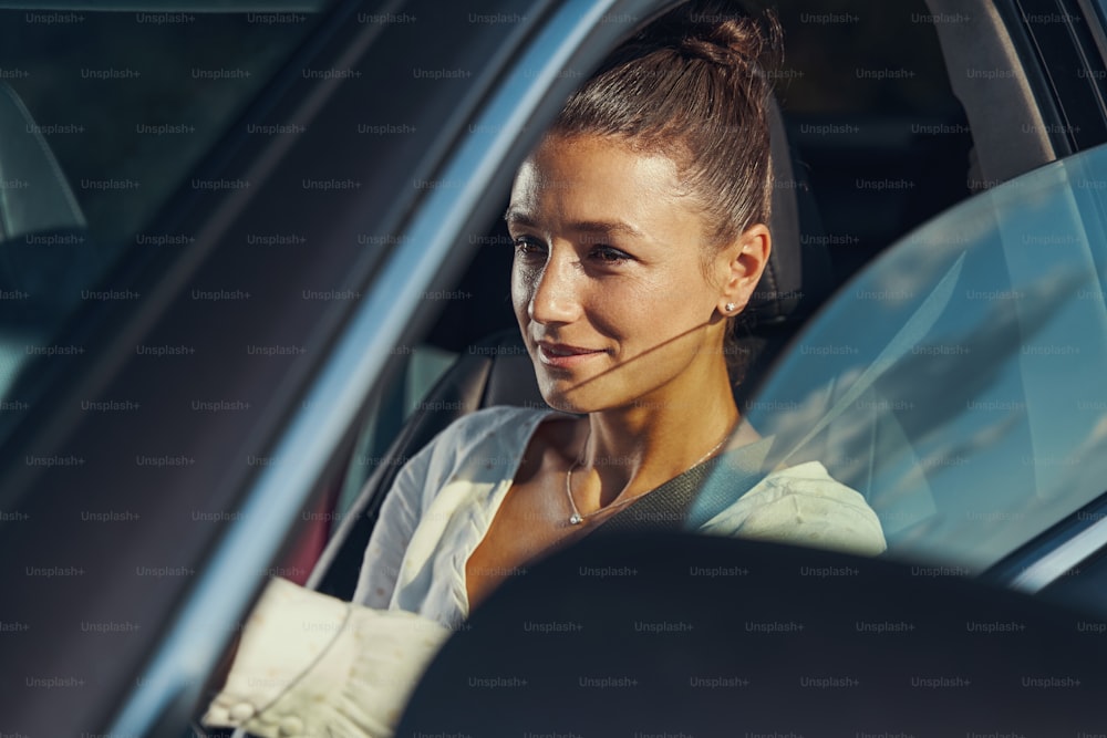 Female with brown tanned skin resting on front seat of car with lowered window