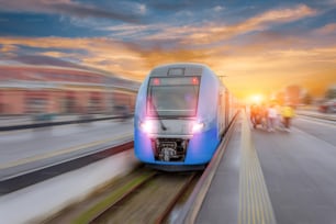 Railway station with modern high speed red commuter train with motion blur effect at colorful beautiful sunset