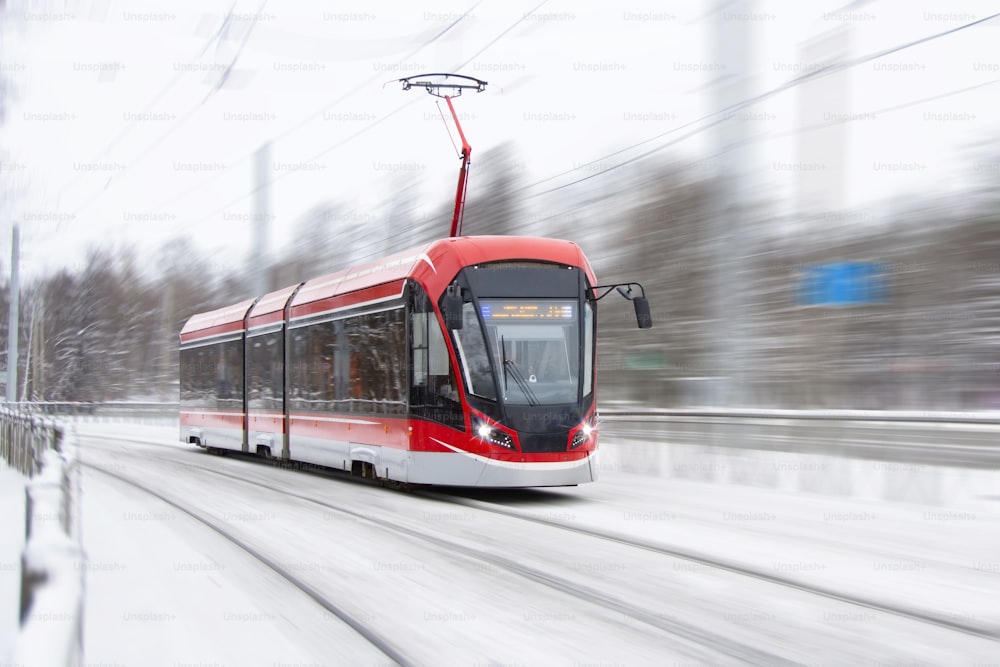 The tram is passing rapidly at a bend in a snow covered city park