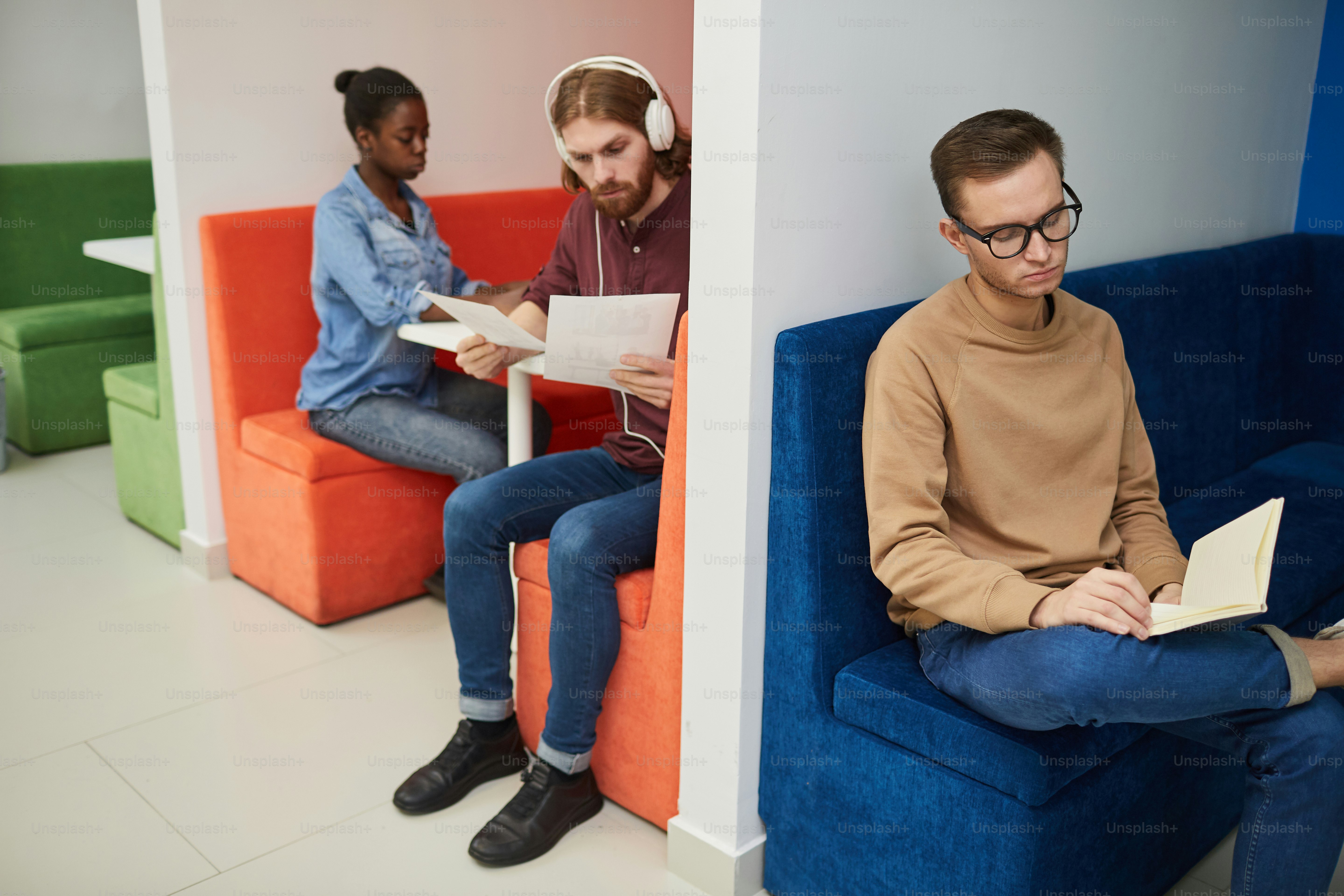 Young people sitting on colorful sofas and reading books and document in the waiting room