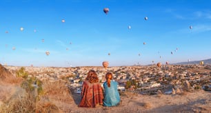 터키의 카파도키아 계곡 위로 멋진 풍선 비행으로 계곡 전망을 즐기는 친구 여행자 몇 명