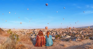 Couple of friends travelers enjoying valley view with wonderful balloons flight over Cappadocia valley in Turkey