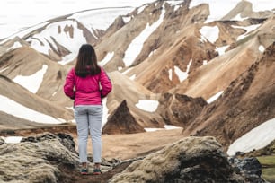Traveler hiking at Landmannalaugar surreal nature landscape in highland of Iceland, Nordic, Europe. Beautiful colorful snow mountain terrain famous for summer trekking adventure and outdoor walking.