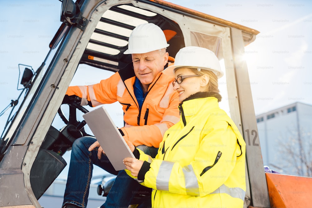 Supervisor woman instructing forklift driver what to work on next