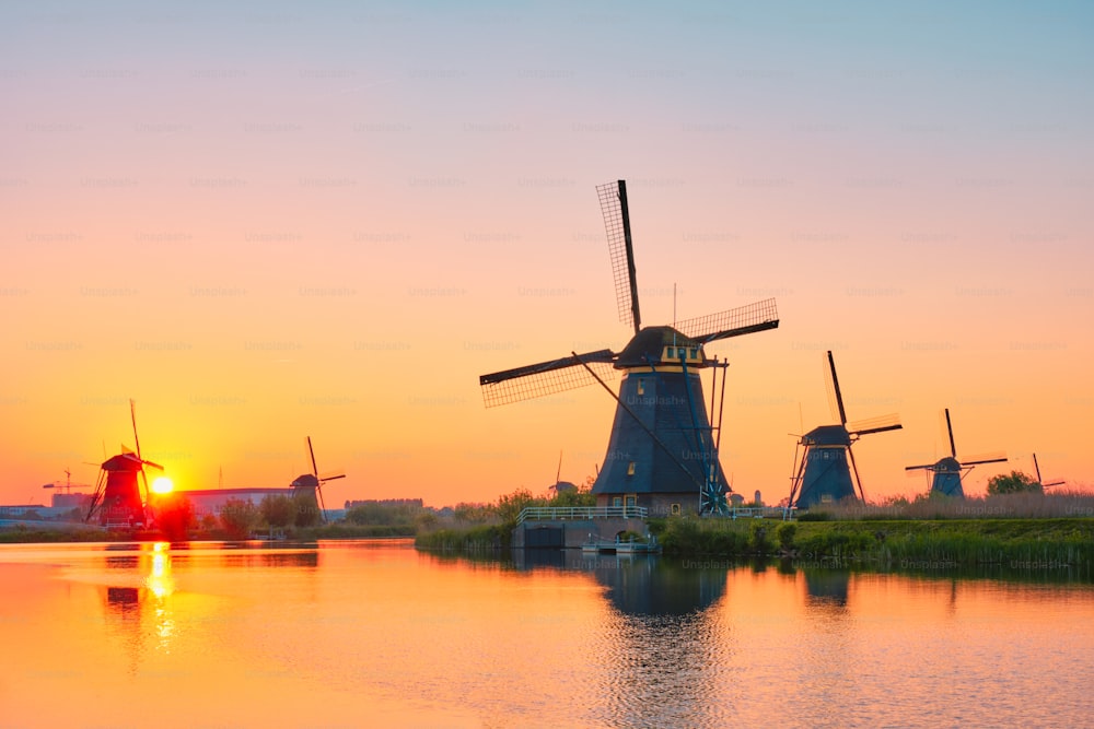 Niederländische ländliche Landschaft mit Windmühlen am berühmten Touristenort Kinderdijk in Holland bei Sonnenuntergang mit dramatischem Himmel