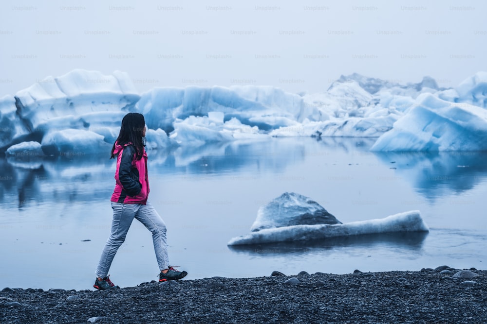 Woman traveler travels to Jokulsarlon beautiful glacial lagoon in Iceland. Jokulsarlon is a famous destination in Vatnajokull National Park, southeast Iceland, Europe. Cold winter ice nature.