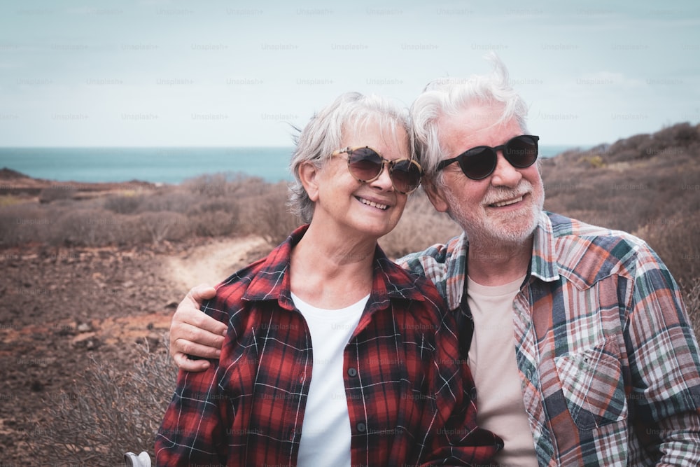 Portrait of beautiful couple of senior travelers enjoying outdoors excursion.  Horizon over sea and sunny day