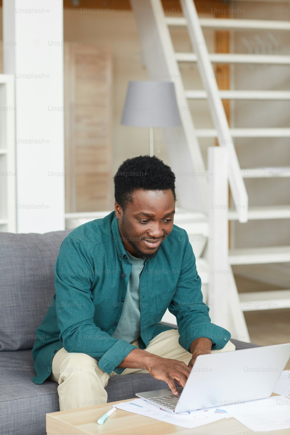 African young man sitting on sofa and typing on laptop computer he working online at home